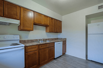 A kitchen with white appliances like a dishwasher and stove and brown cabinets at Sahuaro West, Phoenix 85029.